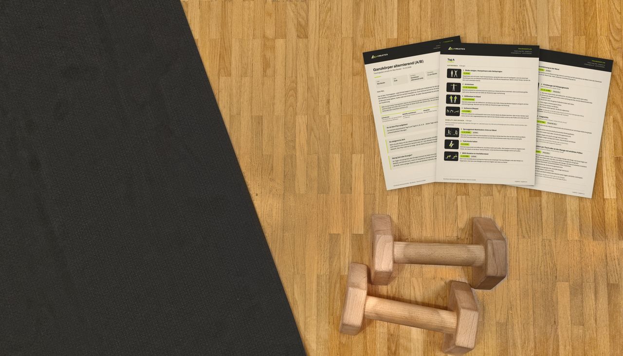 Ausgedruckter Trainingsplan auf dem Parkettboden, daneben Trainingsmatte und Liegestützgriffe