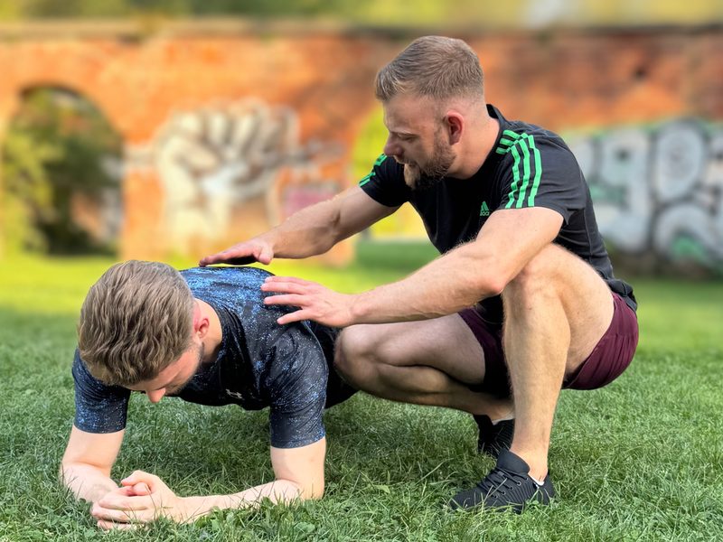 Robert Lang korrigiert beim Personal Training im Park die Haltung eines Klienten